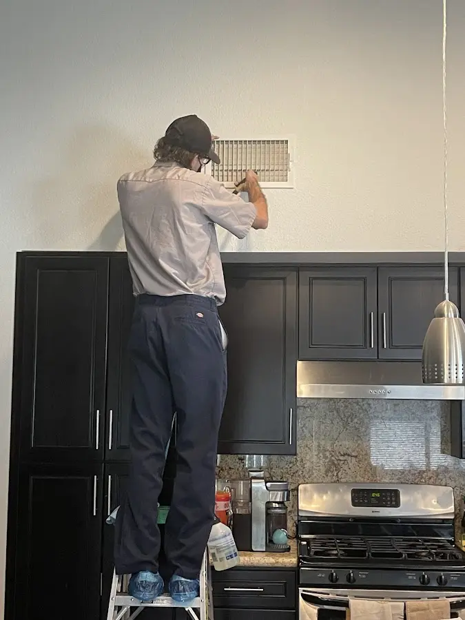 Technician inspecting an air vent during HVAC service in Granger